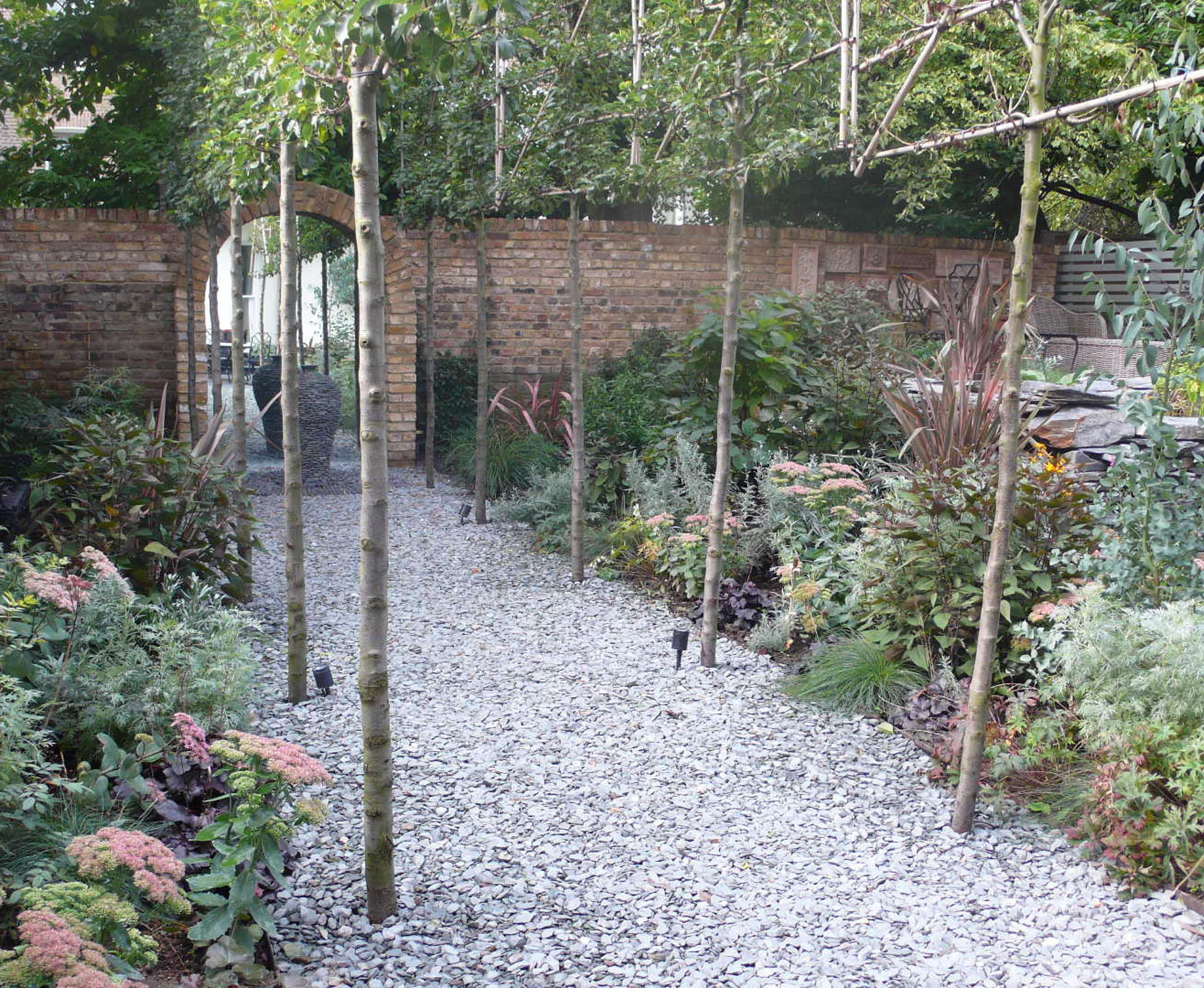The planting overhangs the gravel path, with some nice leaves and texture and a few flowers coming through the seasons. The Belsize Park garden is all about balance in colours and simplicity of materials. 