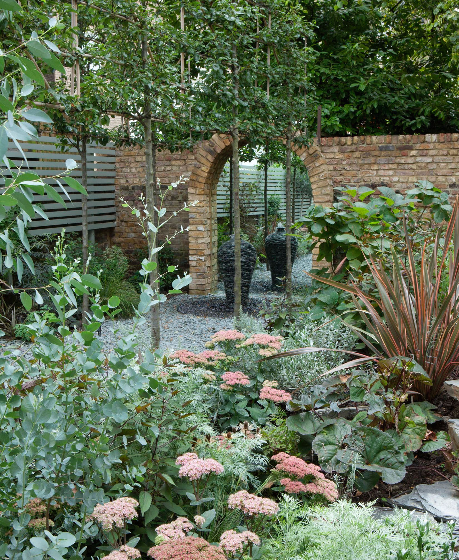 Detail of the planting with some key plants such as Pyrus ‘Chanticleer’, Achillea, Artemisia ‘Powis Castle’, Phormium tenax intermingled to create a wilder effect. The colours are soft and blend in with the existing brick walls and the hard landscaping.