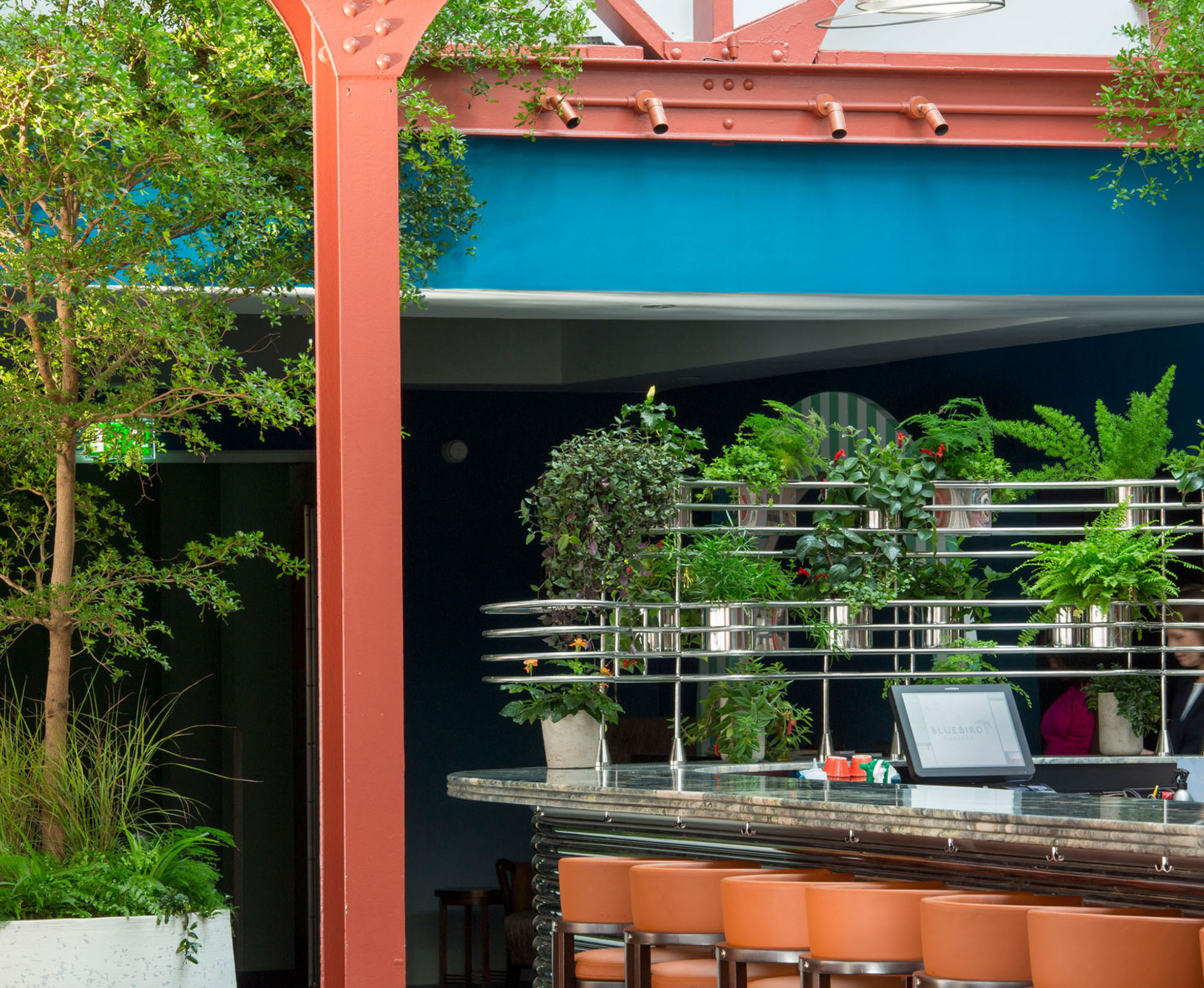 Two trees are positioned in feature Urbis planters at the entrance of Bluebird Restaurant to welcome clients and to create a visual link with the dining area further back. The bar has also been planted for a nice lush effect.