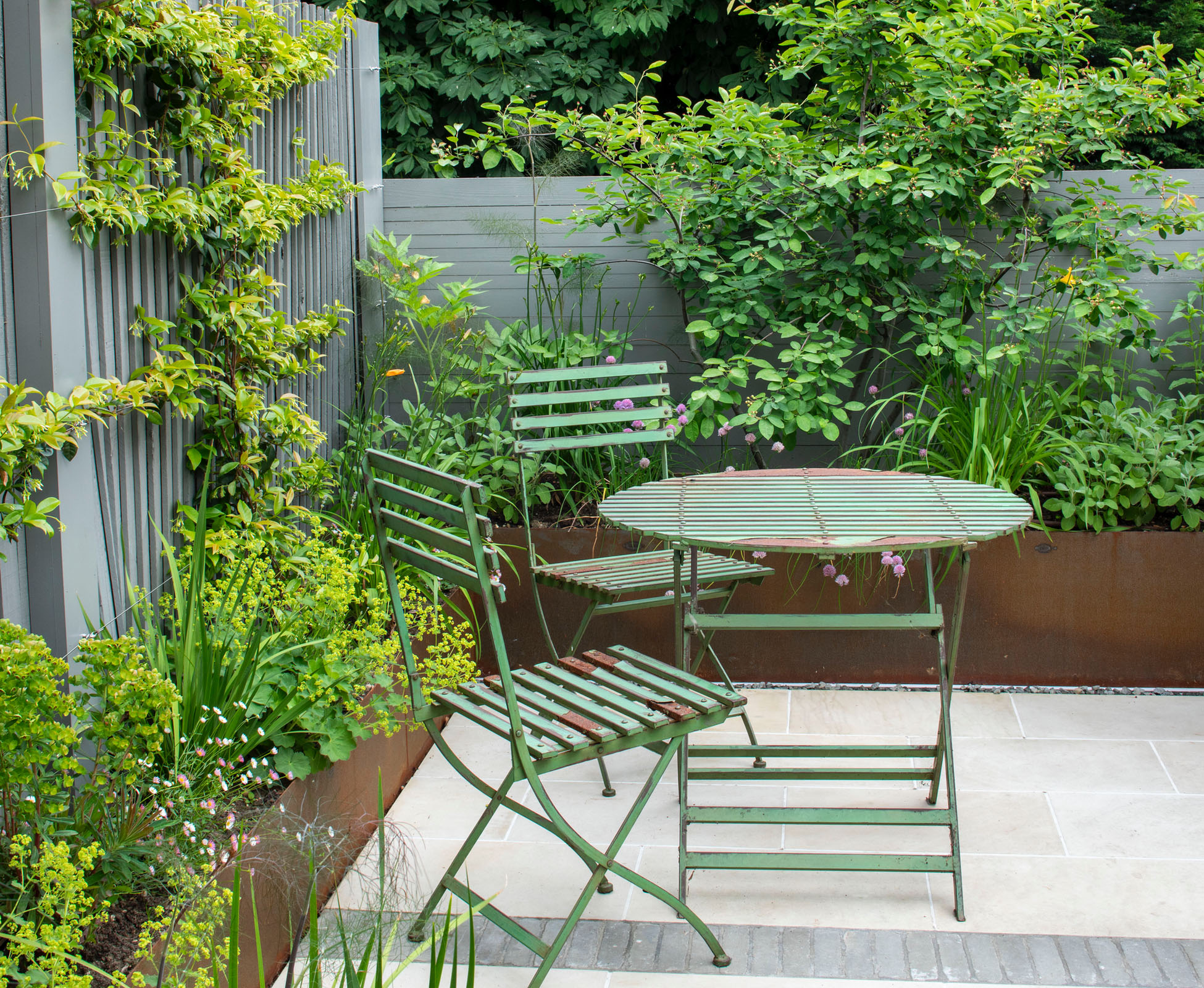 Corten steel planter walls sit above the garage roof and provide planting space for an Amelanchier Lamarckii and some herbaceous plants.