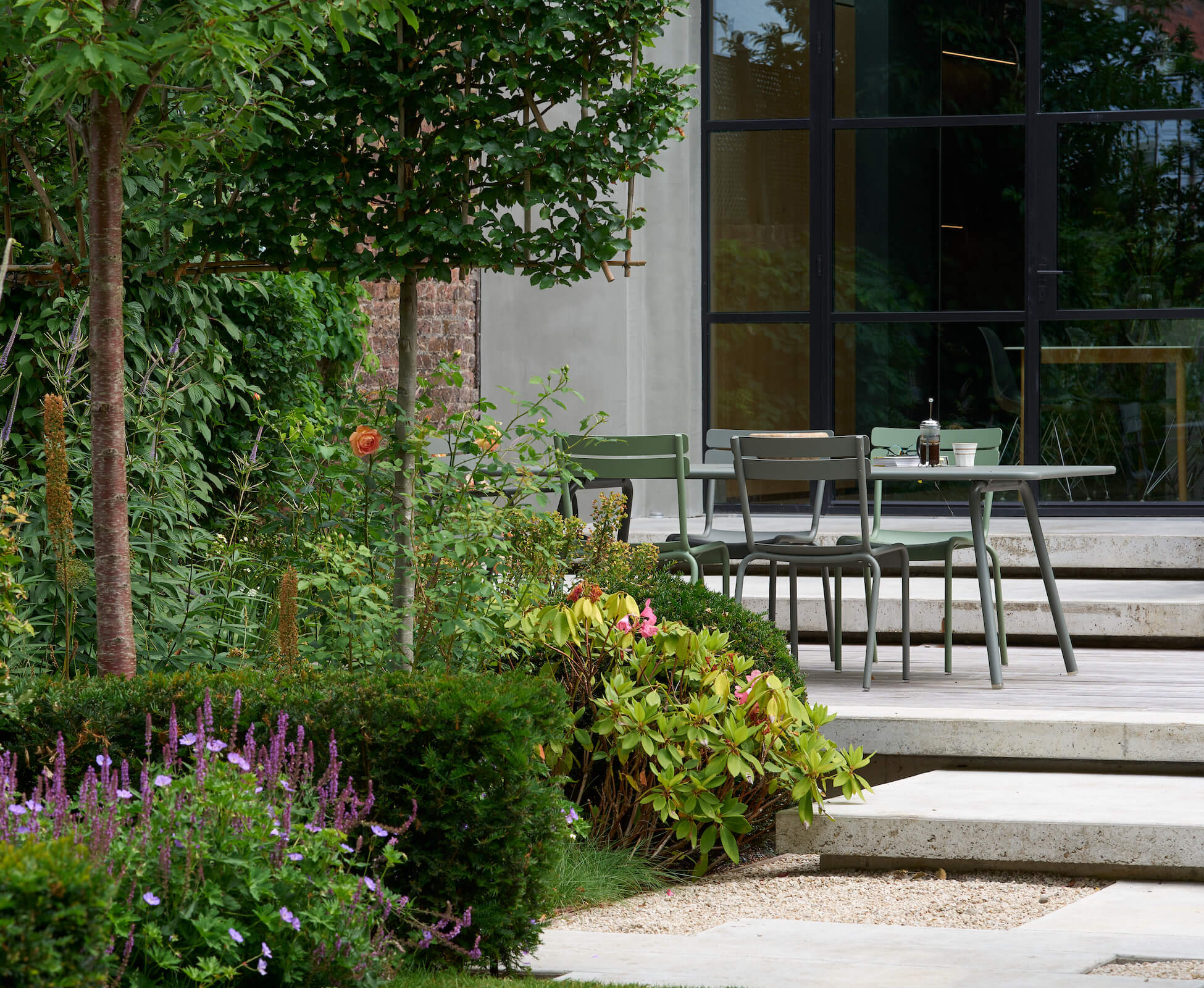 Bringing the planting closer to the house allows for a more sheltered, intimate seating area to entertain or have a peaceful morning coffee. The floating poured concrete steps tie in architecturally with the facade of the remodelled extension.