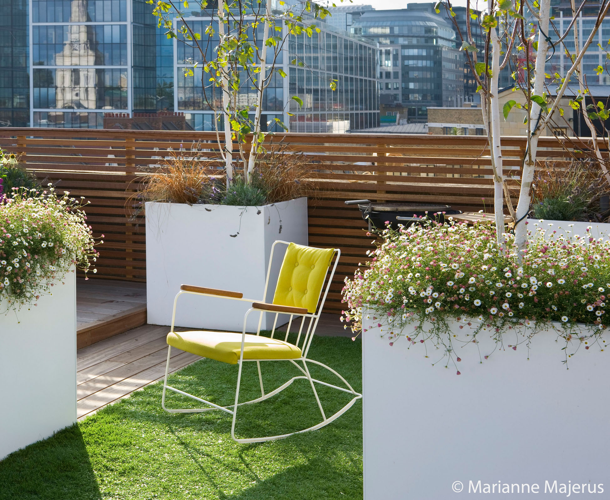 The cosy furniture is welcoming on this city rooftop terrace, where astroturf and timber details create a warm space.