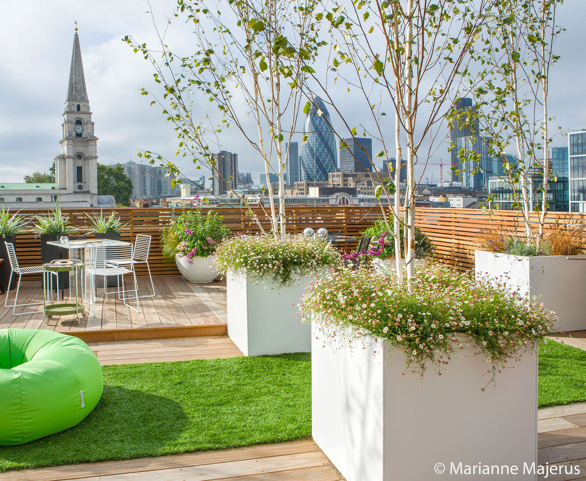 Three white GRP planters planted with some tall multistem birch trees overlook the city’s skyline from this newly designed rooftop terrace.