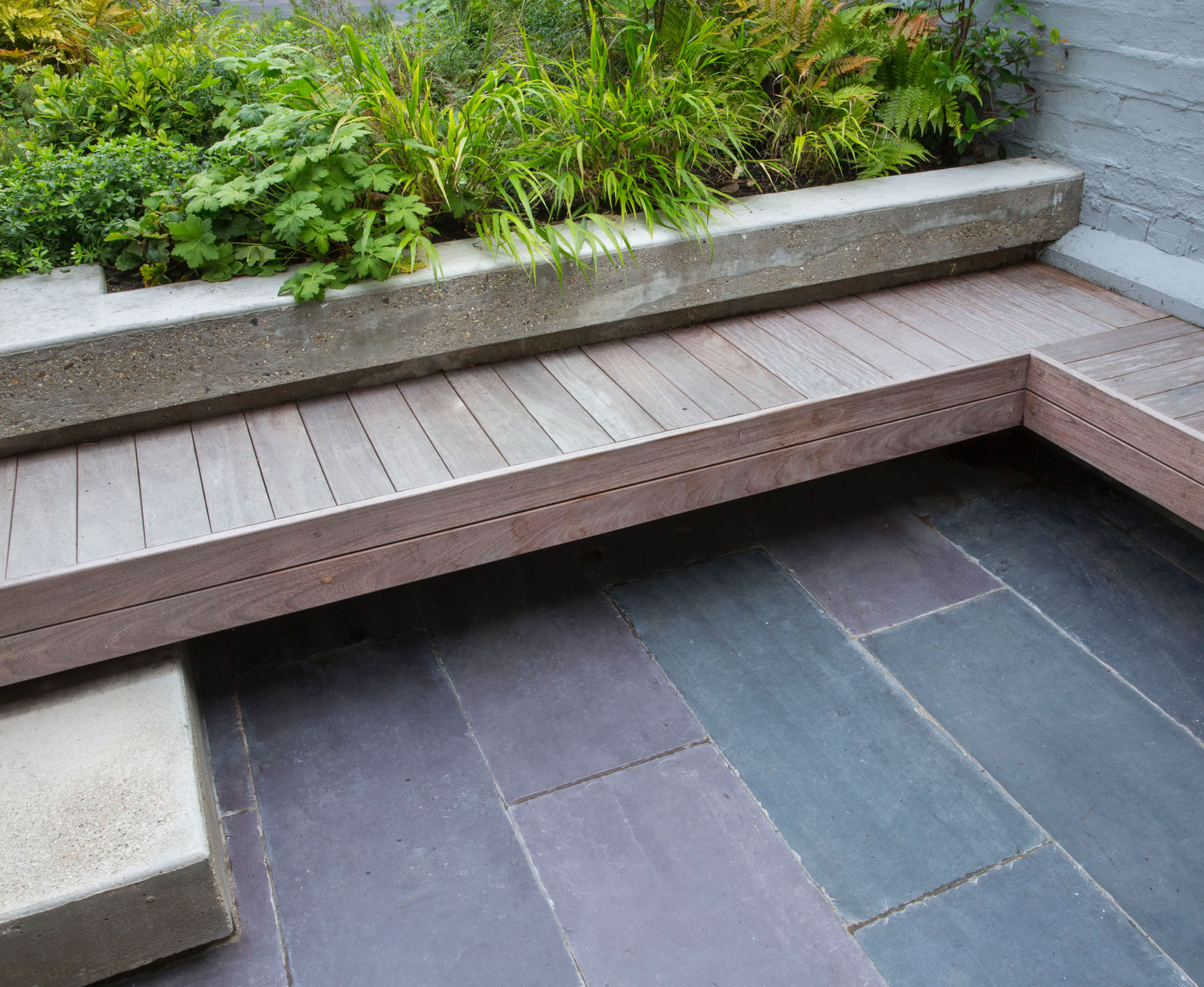 The hardwood ipe bench wraps around the reclaimed slate paving in the lower patio. It faces the kitchen and when the french doors are open, becomes part of the house.