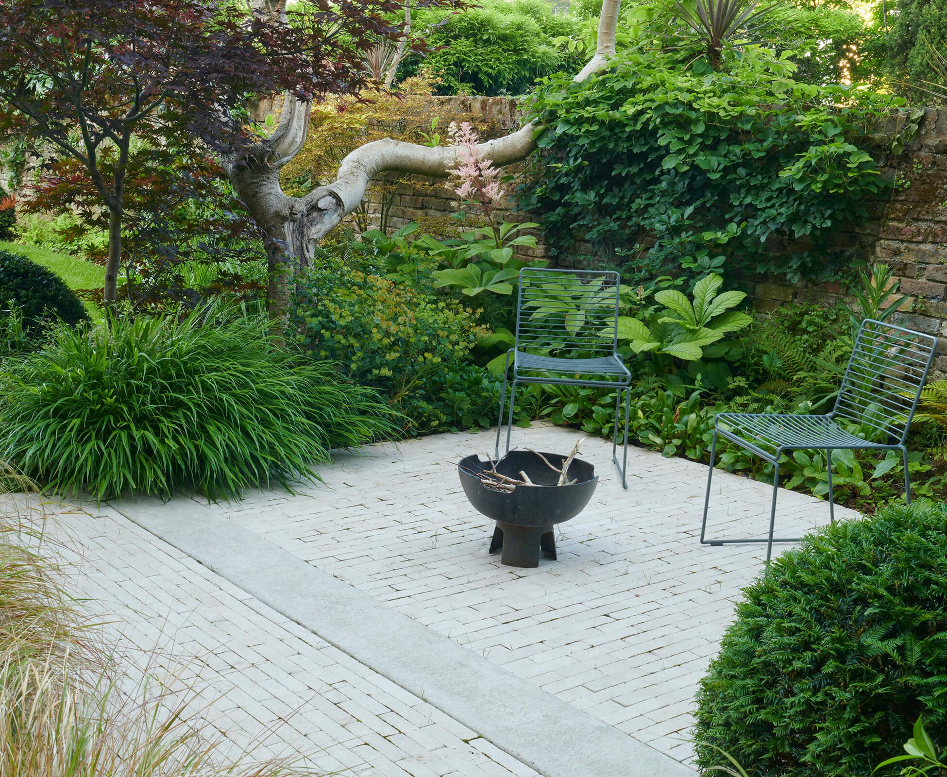 A hidden seating area at the back of the garden, enclosed by plants for privacy.