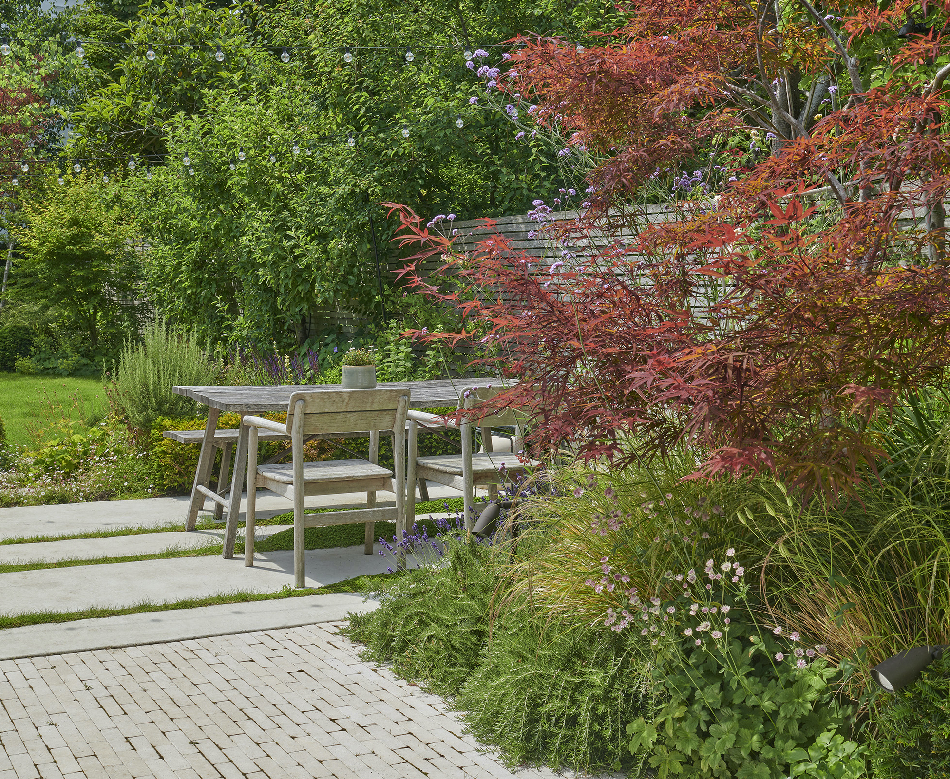 Overview of the garden path, made with alternating smooth concrete and stone pavers. The path links the main patio to the dining area and continues toward the garden studio at the back of the garden