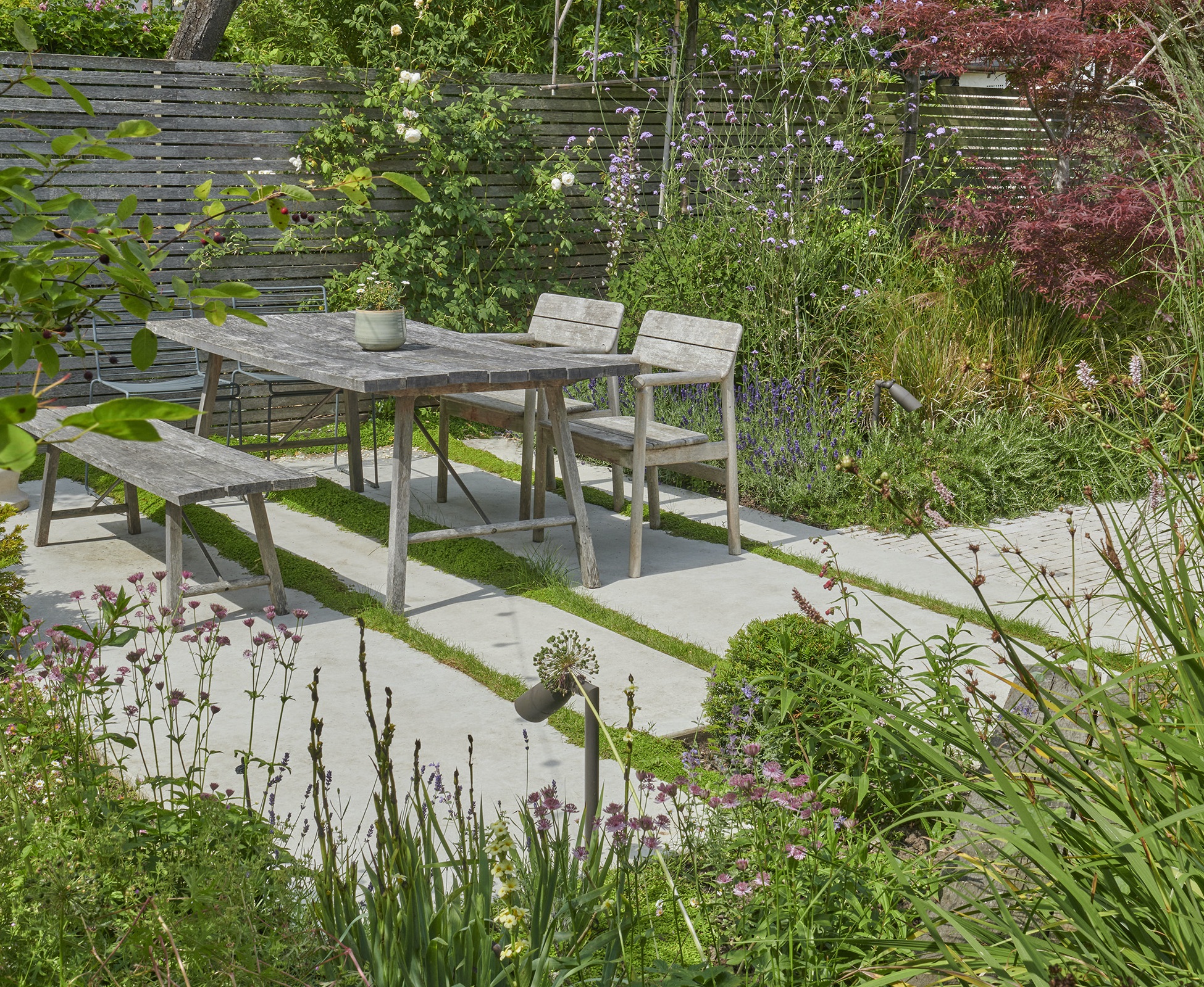 The main dining area sits on smooth concrete platforms, surrounded by lush planting.