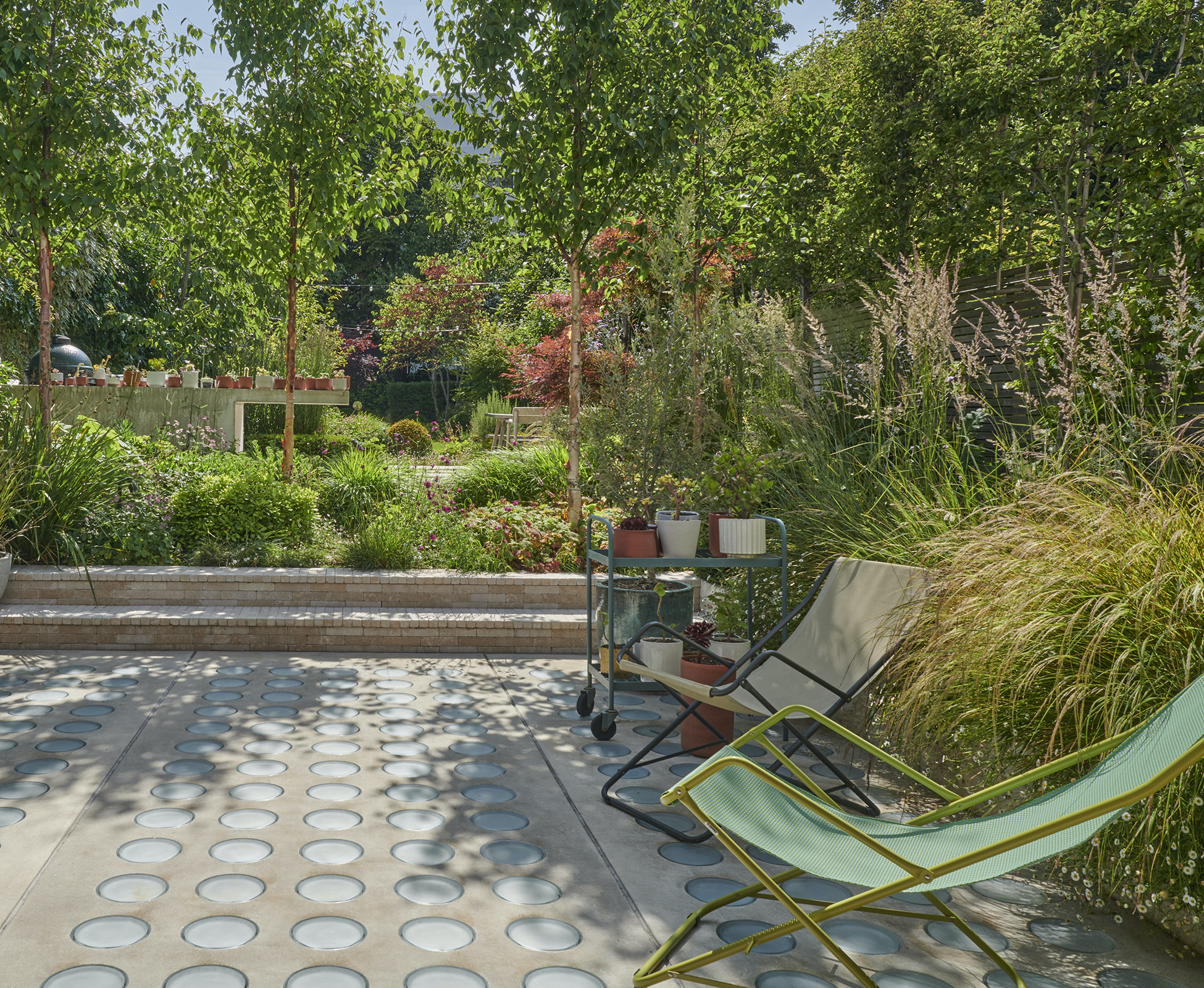 Overview of this Hampstead rear garden from the patio, surrounded by greenery, creating a peaceful and serene atmosphere for the owners.