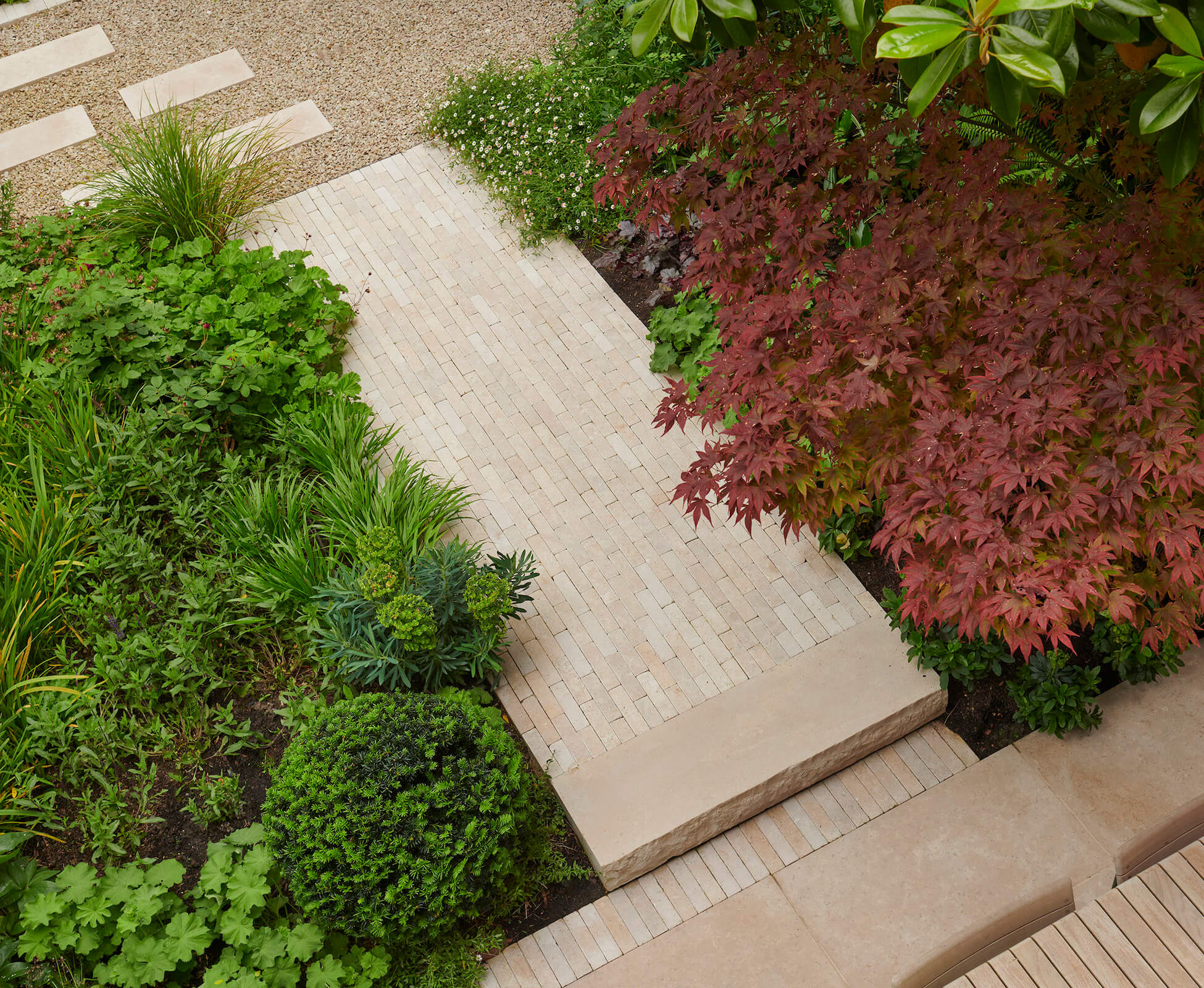 An attractive limestone paver path visually connects to the house window and draws the eye across the garden.