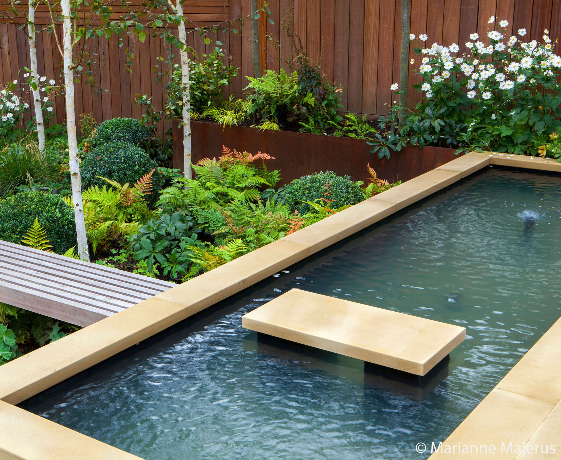 Detail of the coping stones around the water feature and the hardwood seat that also acts as a boardwalk through to the woodland planting area.