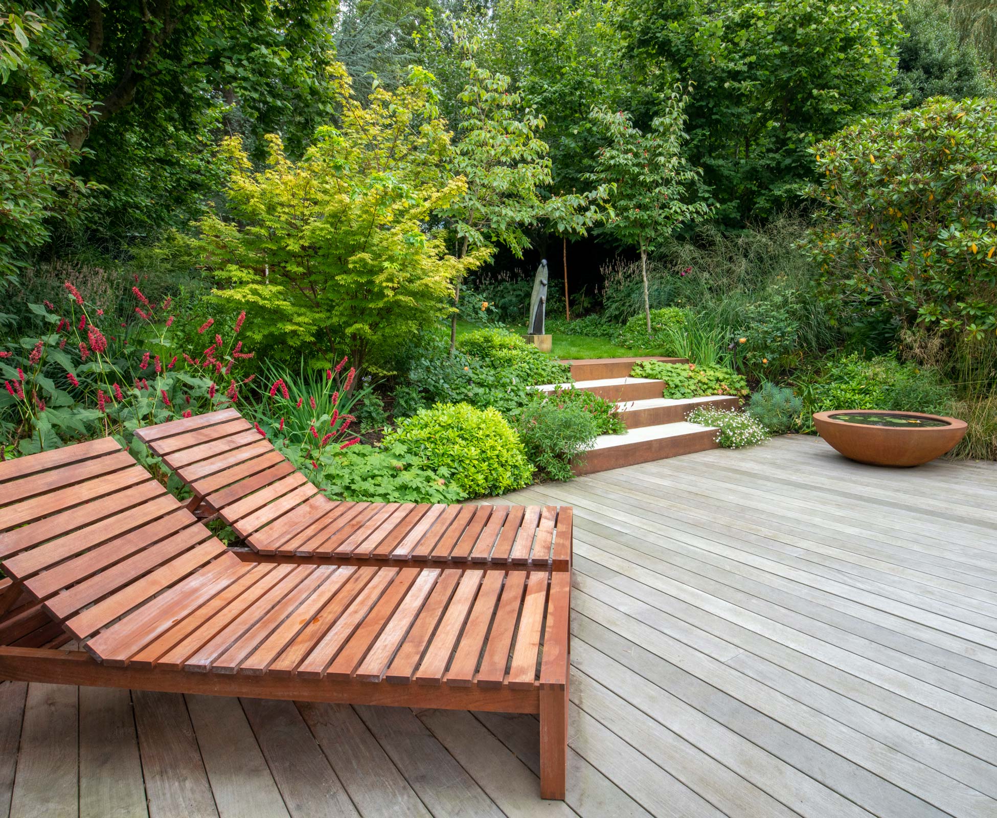 Hardwood timber deck has aged naturally to a silver grey. The corten details tie in with the timber of the deck chairs.