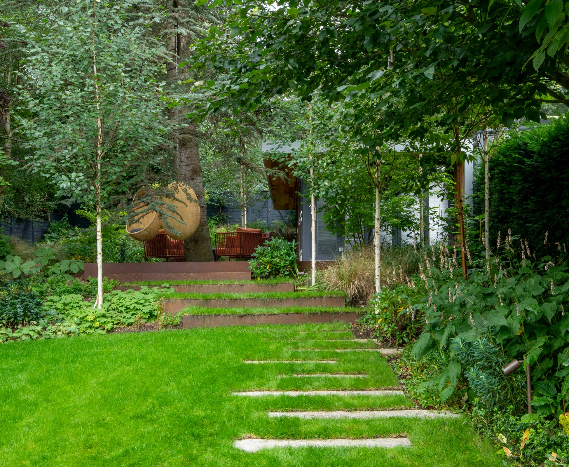 The staggered poured concrete stepping stones create a gentle meandering journey through the lawn up to the rear woodland garden.
