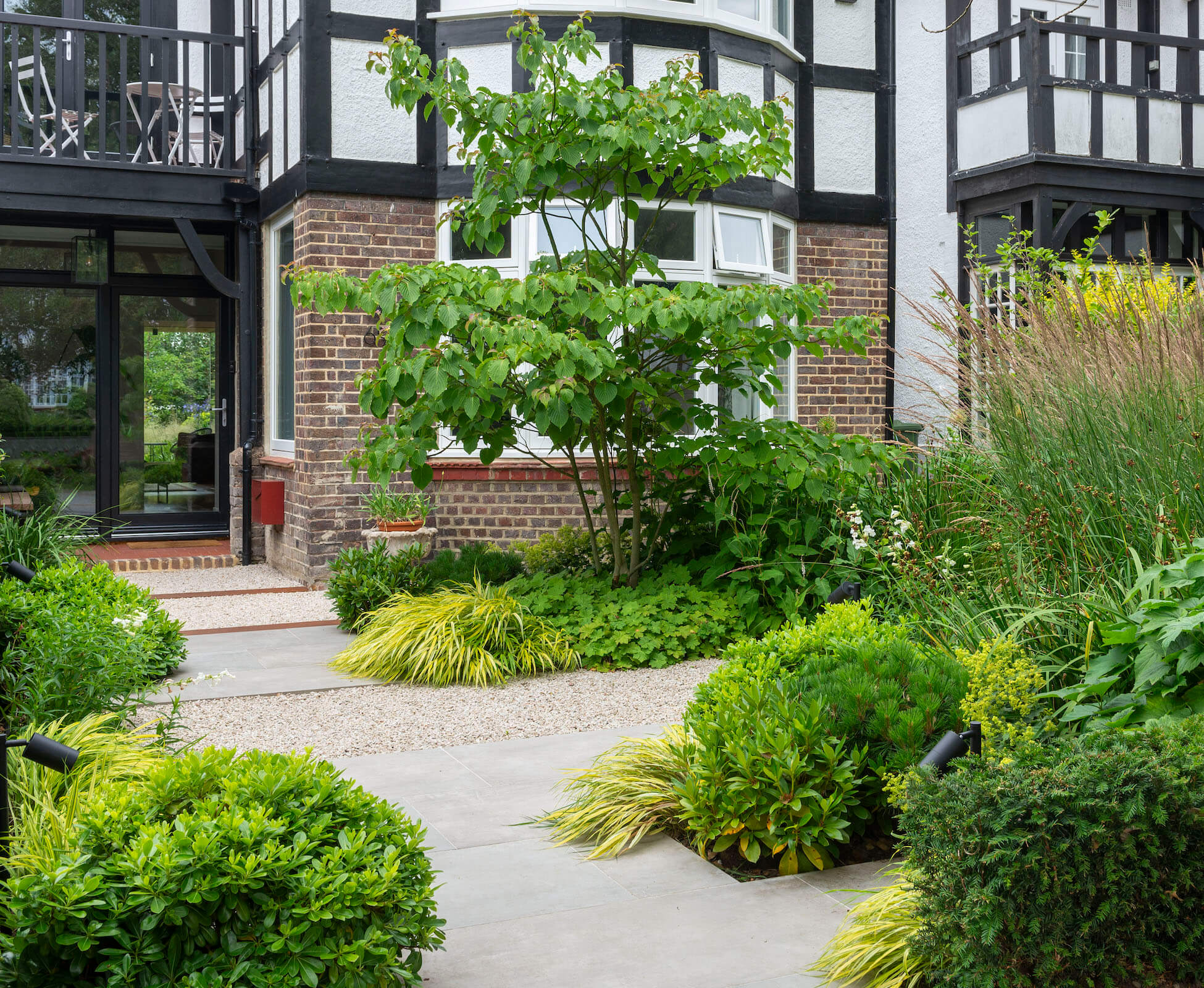 In the front garden, tantalising glimpses through the glass doors, entice you down the staggered garden path.