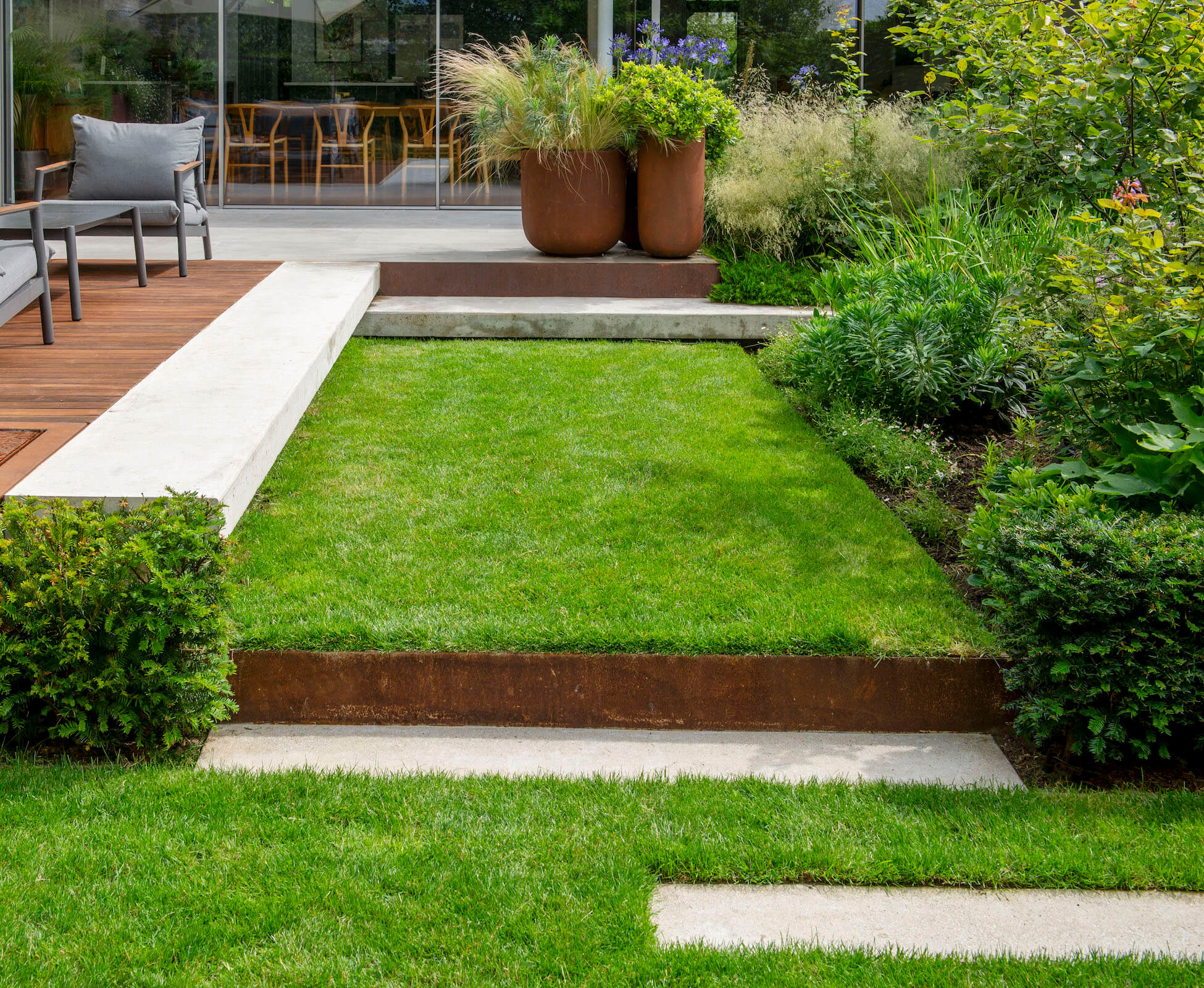 The design layout of the garden followed the architectural lines of the modernist extension, using poured concrete and accents of corten steel.