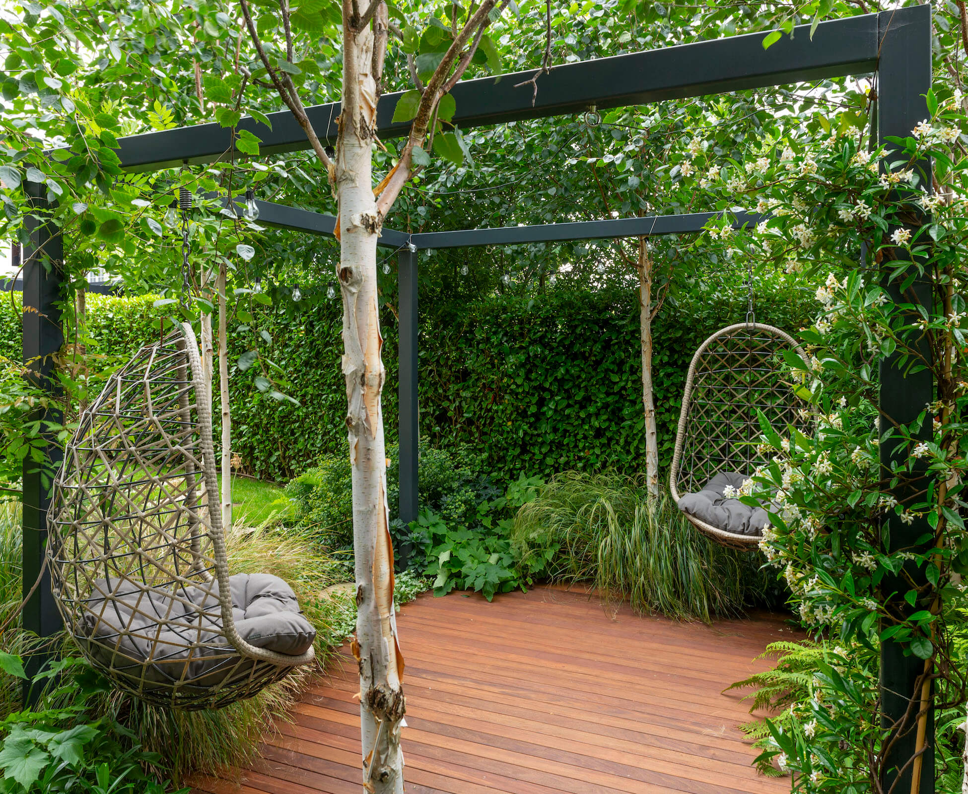 Evergreen jasmine is woven around the vertical posts of the powder-coated steel pergola.