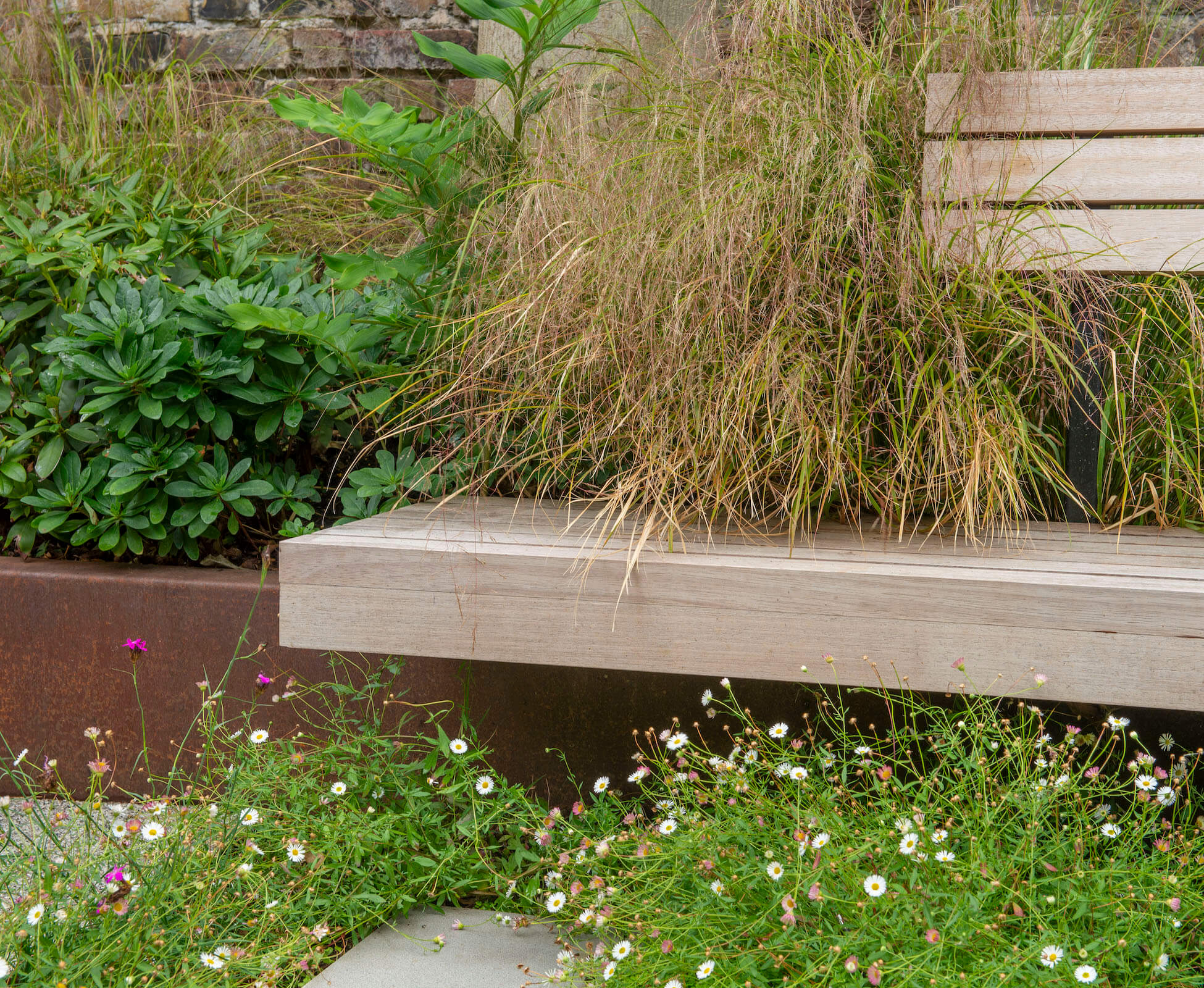 The bespoke hardwood bench was designed to cantilever off the corten planter and sit above the roots of the existing Sycamore tree.