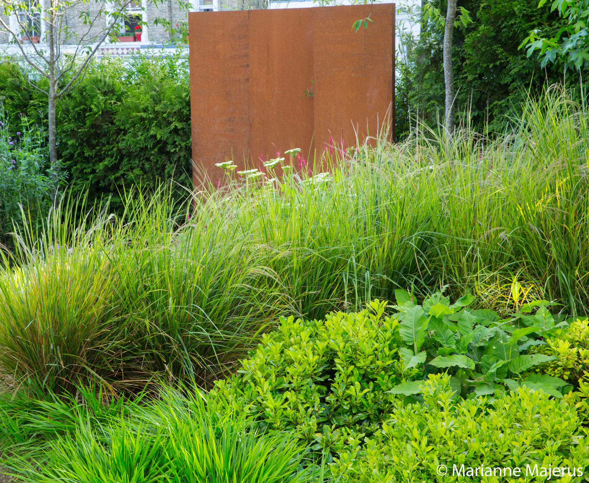 The corten feature panel in this North London garden has been designed and built to contrast nicely with the shades of green of the herbaceous borders.
