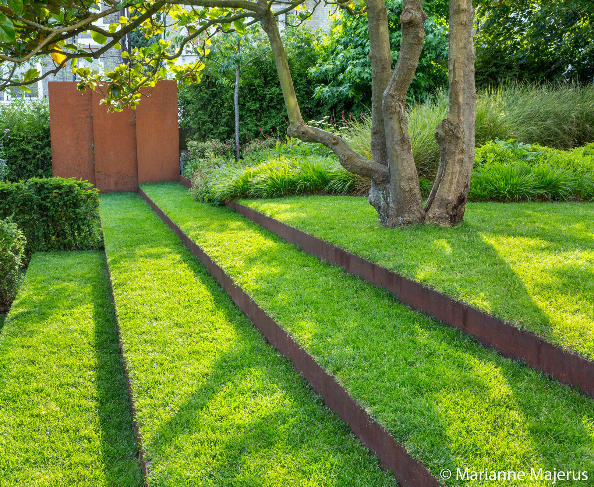 The turf steps and corten risers draw your eye to the feature panels in front of the yew hedge.