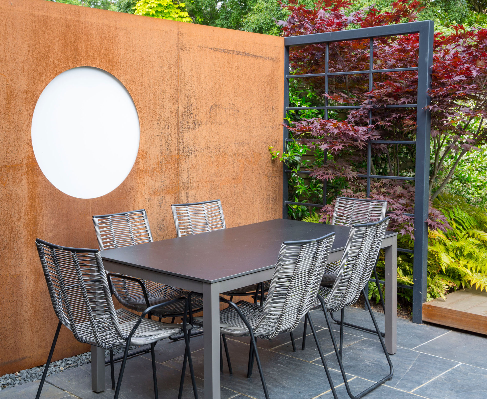 The corten steel feature wall has been installed in front of the neighbour’s unsightly wall. A circle has been cut out and filled with white perspex. There are three circles in this garden, becoming a strong element of the design.