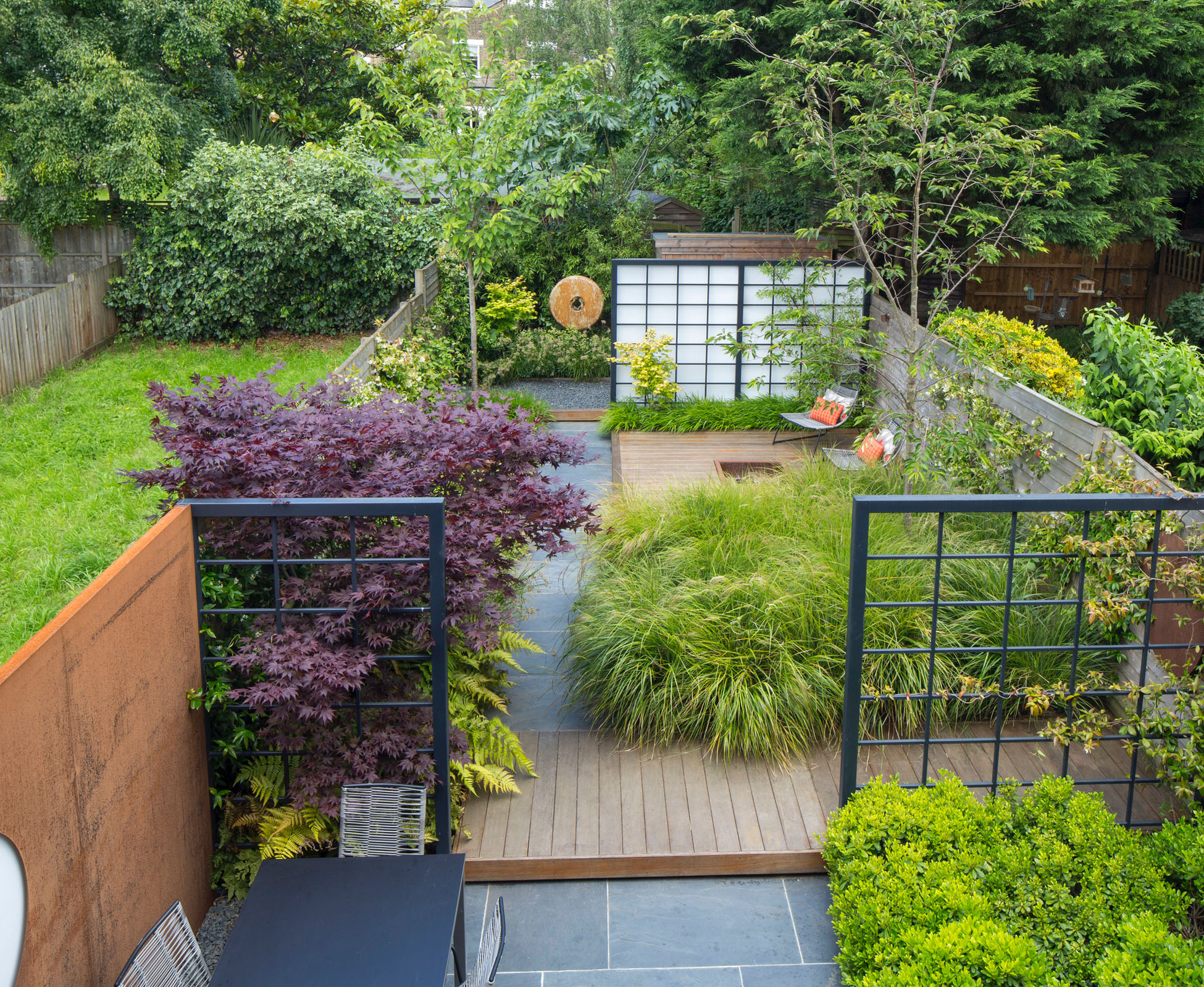 The view from the top floor of the Queen’s Park house shows the entire garden, looking bigger and deeper than is used to before the design was completed. The Acer palmatum ‘Atropurpureum’ is a key feature to be enjoyed from the windows. At the back, a wooden sculpture attracts one’s eye.