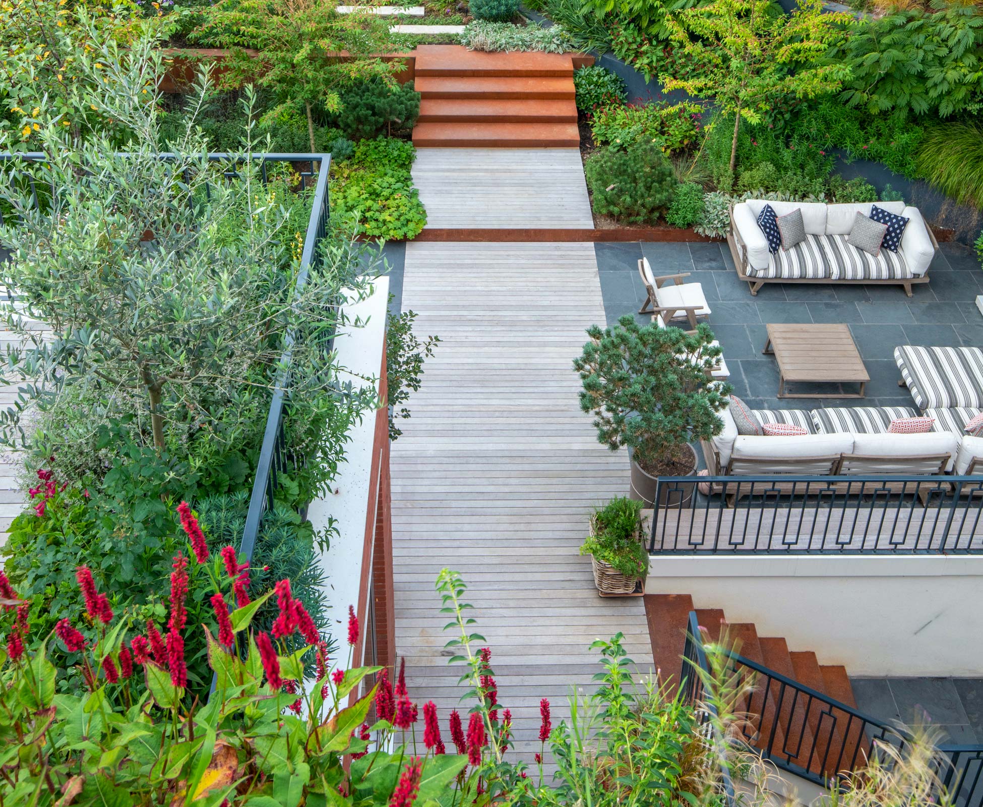 Stunning view of the patio showing wide corten steel stairs connecting the patio area to the raised planting area. A second corten steel staircase connects the patio to the basement terrace of the property.