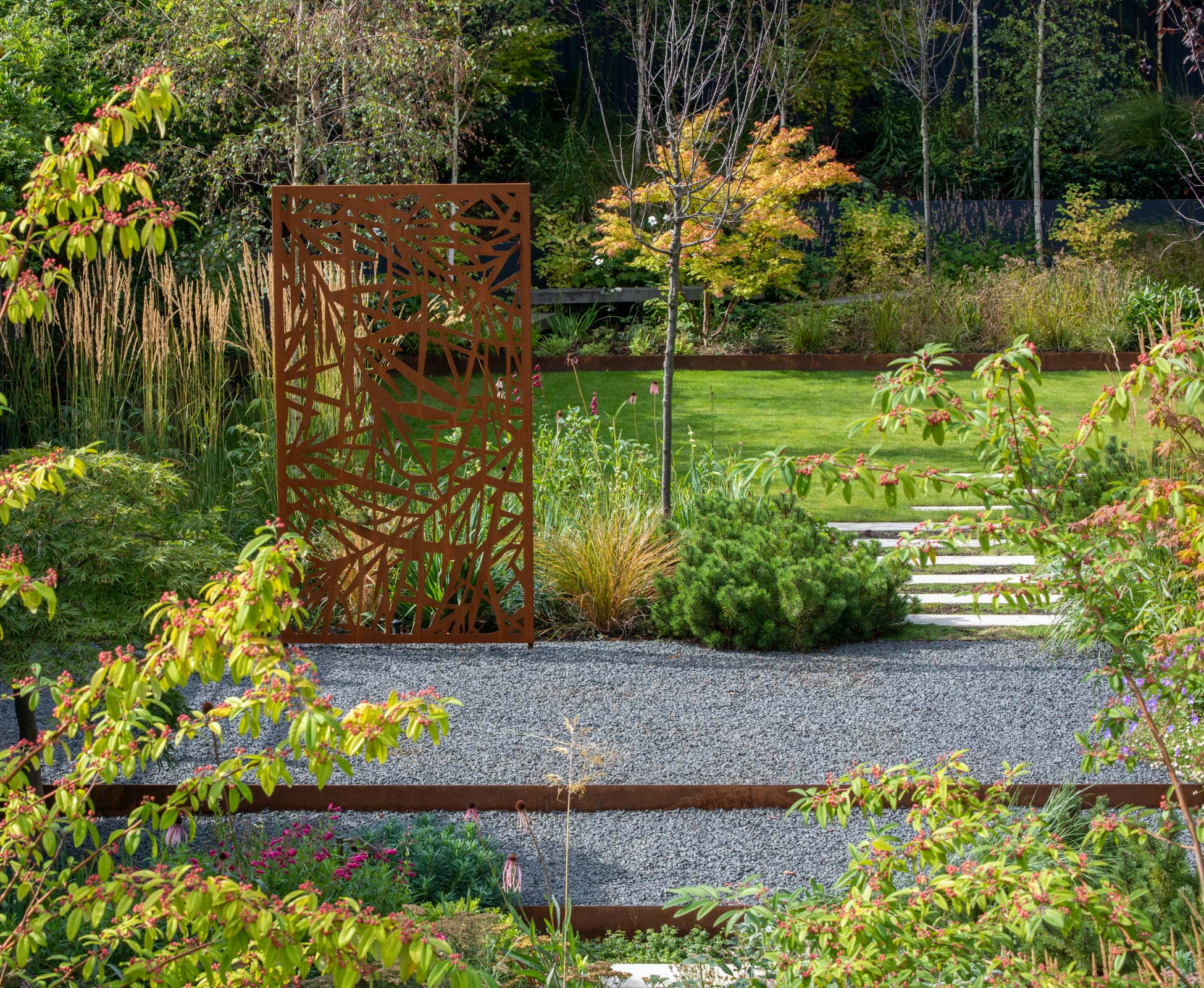 The grey limestone chipping of the gravel emphasises the rusty tones of the beautiful laser cut panel.