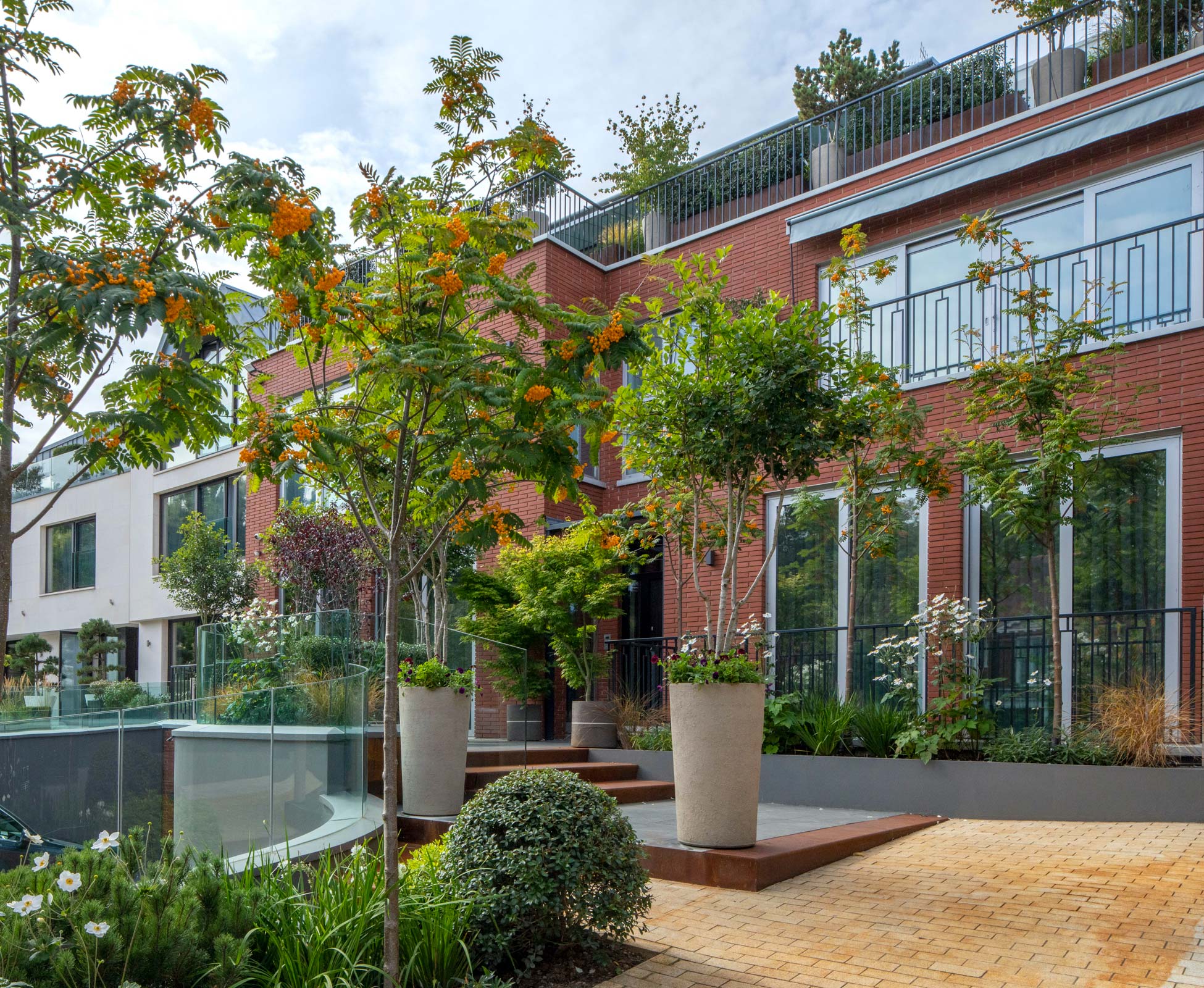 Subtle intervention in the front garden, using corten steel, slate and repainting the existing walls; gorgeous Atelier Vierkant pots planted with Amelanchier and Sorbus trees frame the front entrance access.