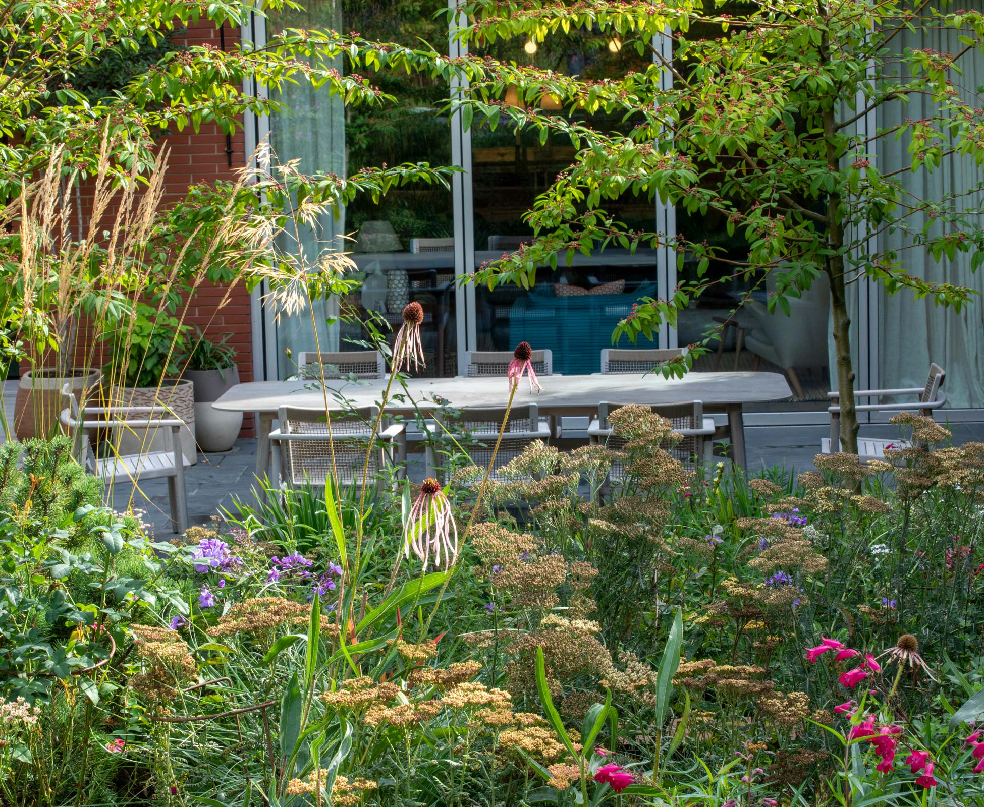 Charming view of the patio at The Villa, layered planting creates an oasis of lush delicate greens.