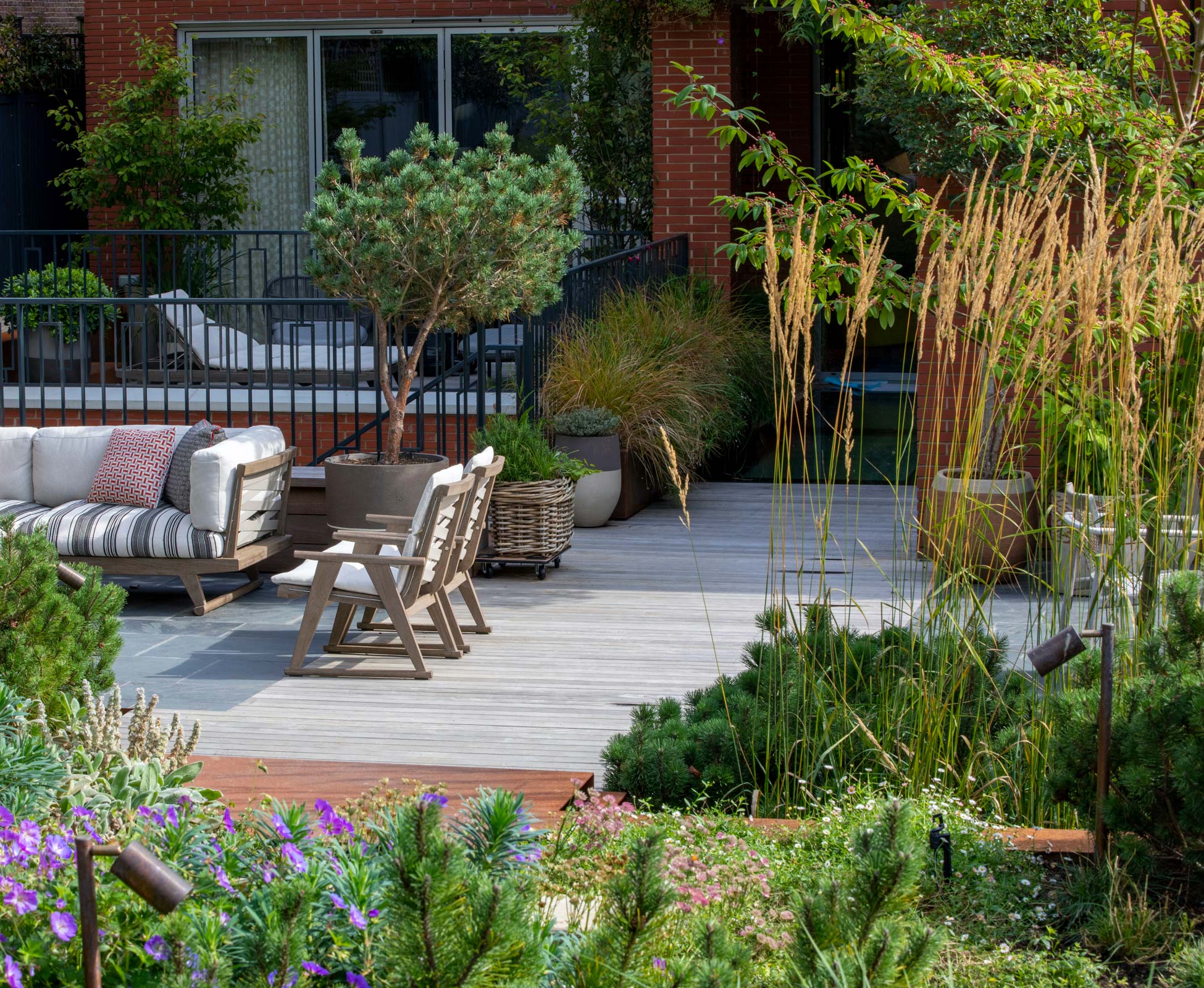 A comfortable outdoor furniture on the patio area enveloped in Calamagrostis 'Karl Foerster' tall grasses.