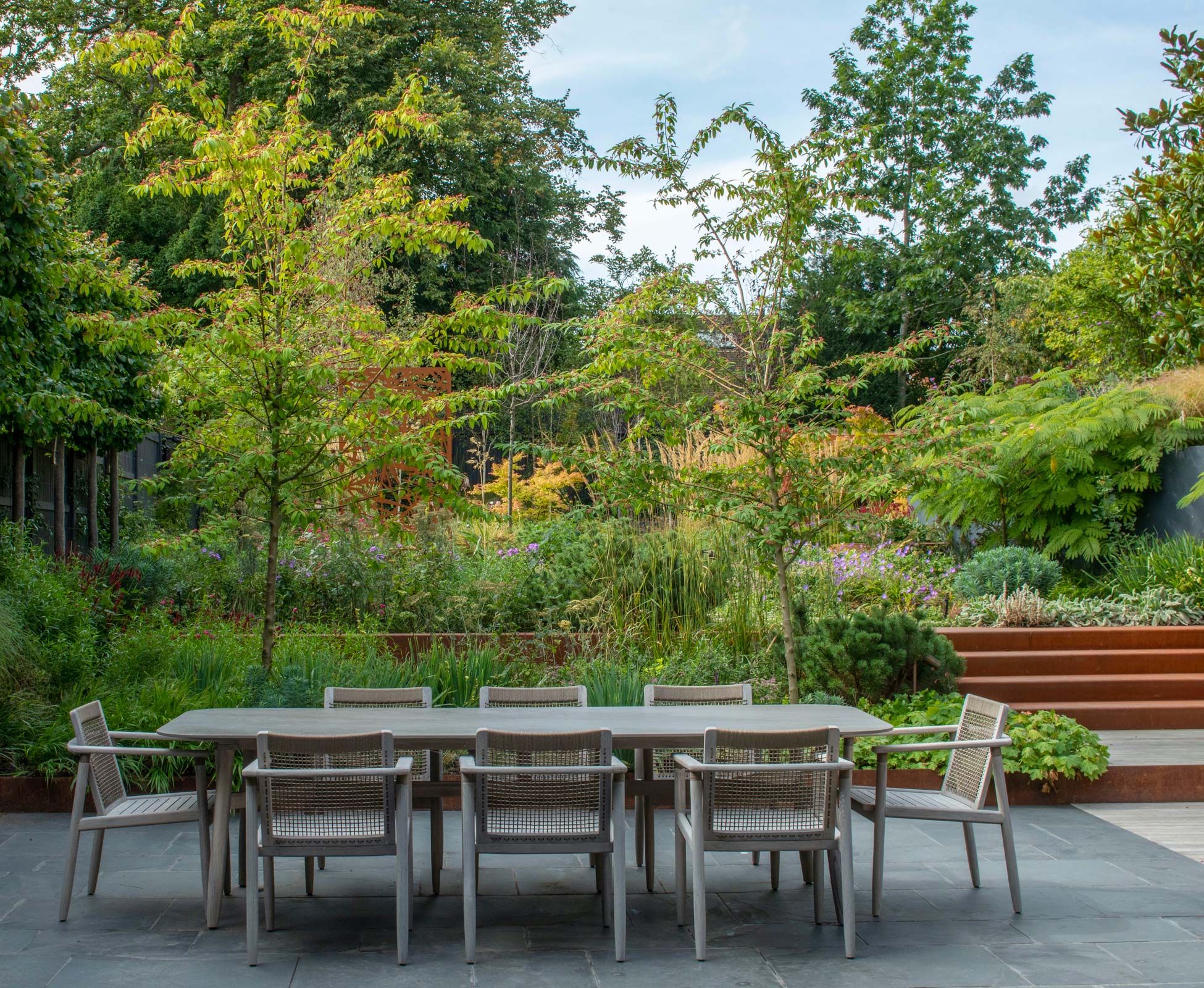 The Villa dining area, the patio is tiled with dark slate creating a lovely contrast with the rusty finish of the corten steel used to build the steps and planting beds.