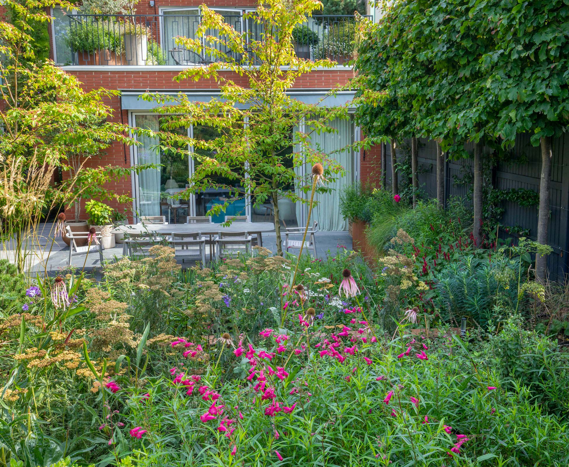 Soft herbaceous planting surrounds the lower dining area