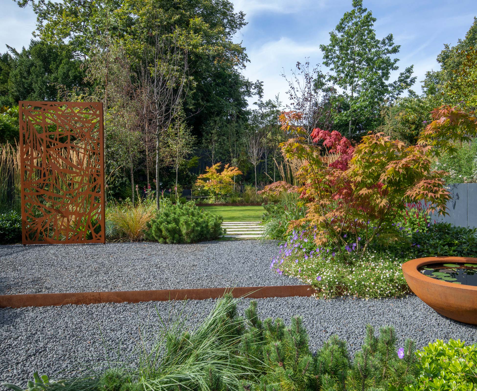The grey limestone chipping of the gravel emphasise the rusty tones of the beautiful laser cut panel.
