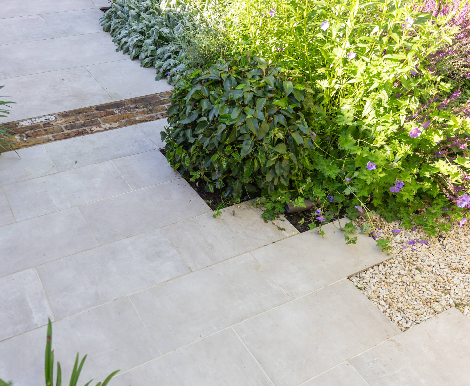 Staggered paving in porcelain is offset with london stock brick banding strips, to visually widen and break up the path leading to the studio.