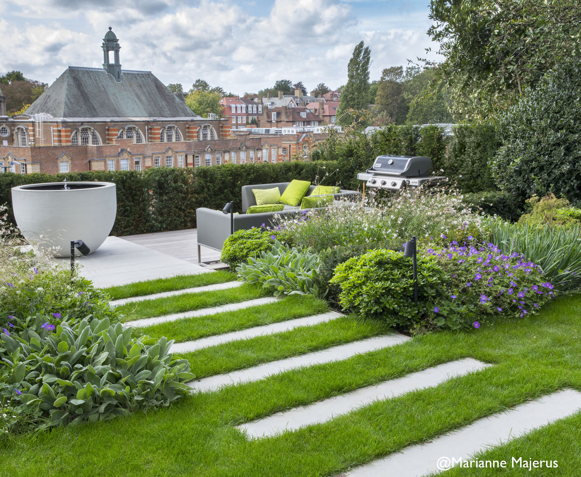 The skyline of london creates a dramatic backdrop to this cantilevered deck, where a BBQ and lounge area draw the family out for evening entertaining.